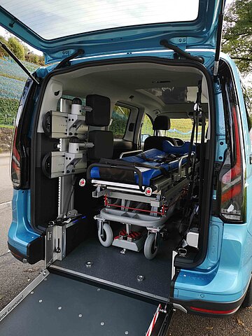 Das Bild zeigt ein Fahrzeug mit Heckausschnitt 86 und ausgeklappter Rampe zur Beförderung eines liegenden Passagiers.