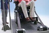 Frau im Rollstuhl wird über das Inqline-System in das Fahrzeug gefahren