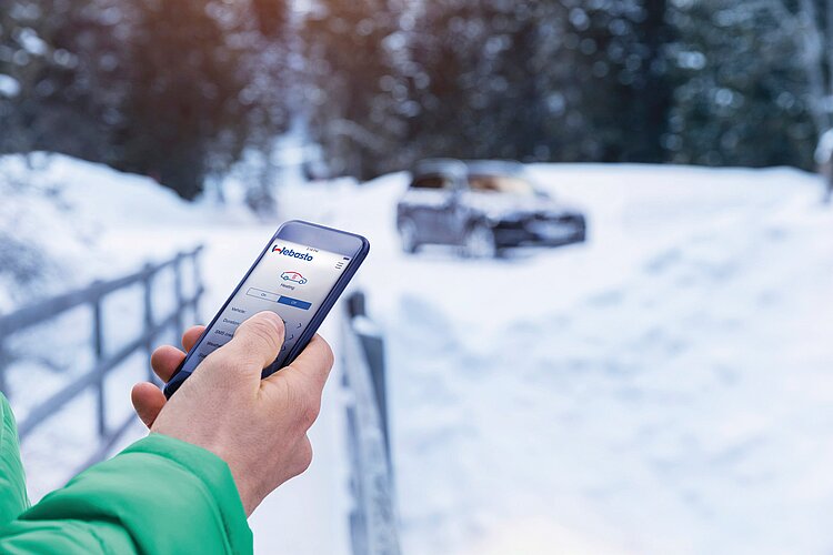 Un uomo aziona il riscaldamento ausiliario della sua auto tramite app